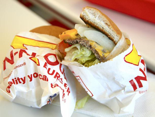 An In-N-Out burger that has been cut in half and are sitting in wrappers