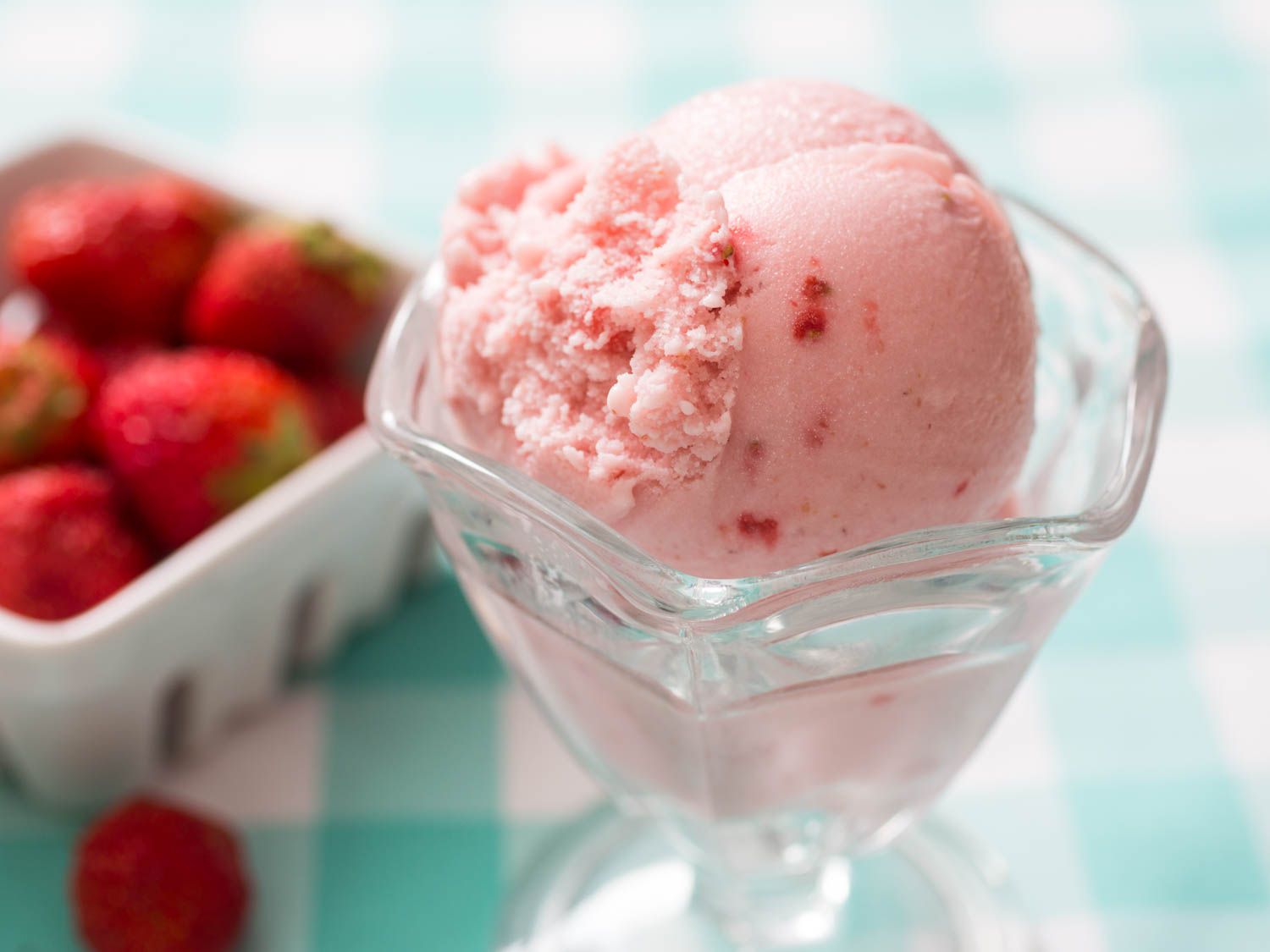 A small parfait glass holding a scoop of strawberry ice cream.