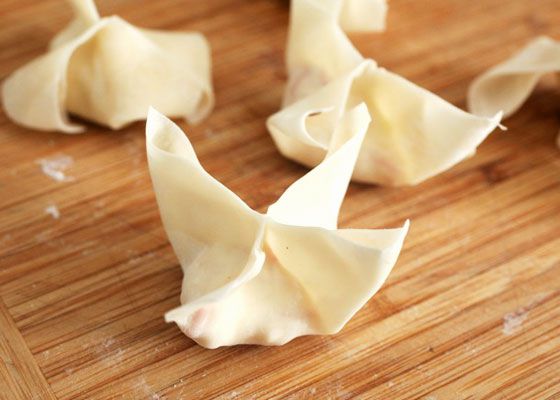 Folded crab rangoon on a wooden cutting board