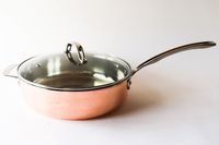 Copper saucepan with a glass lid and a stainless steel handle