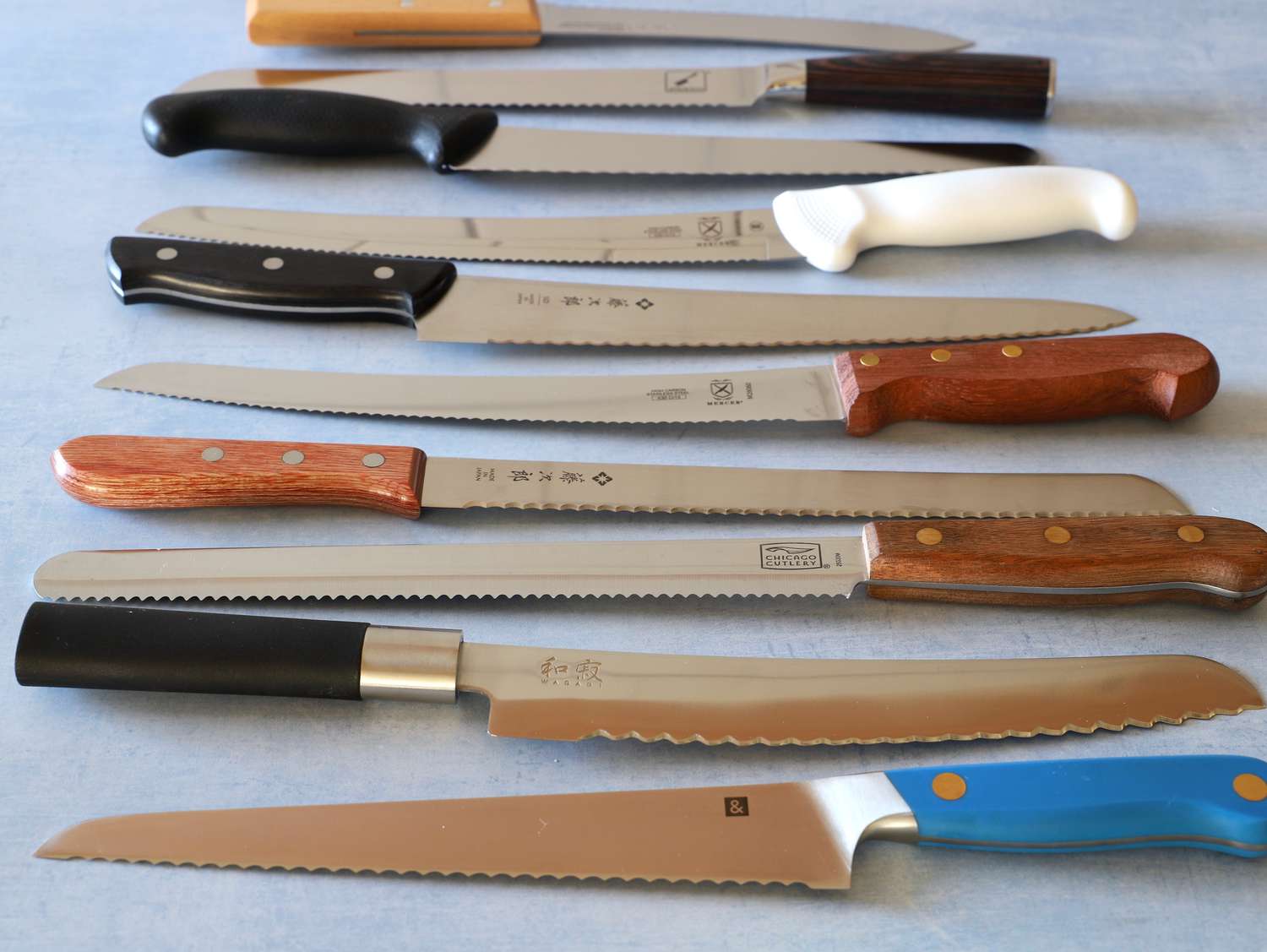 Group of bread knives displayed on a blue surface