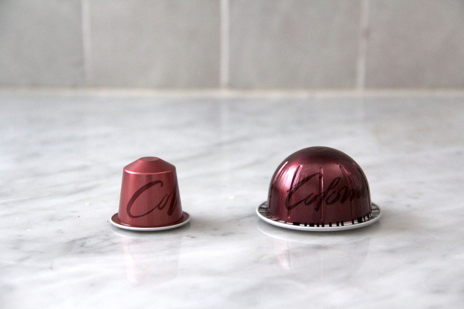 Two Nespresso Columbia pods on a marble countertop.
