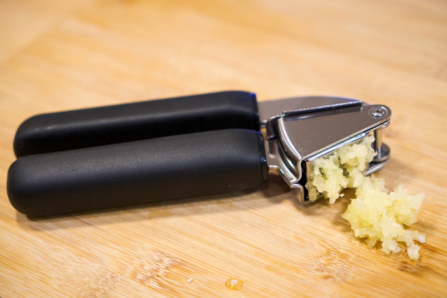 A garlic press with minced garlic on a wooden surface