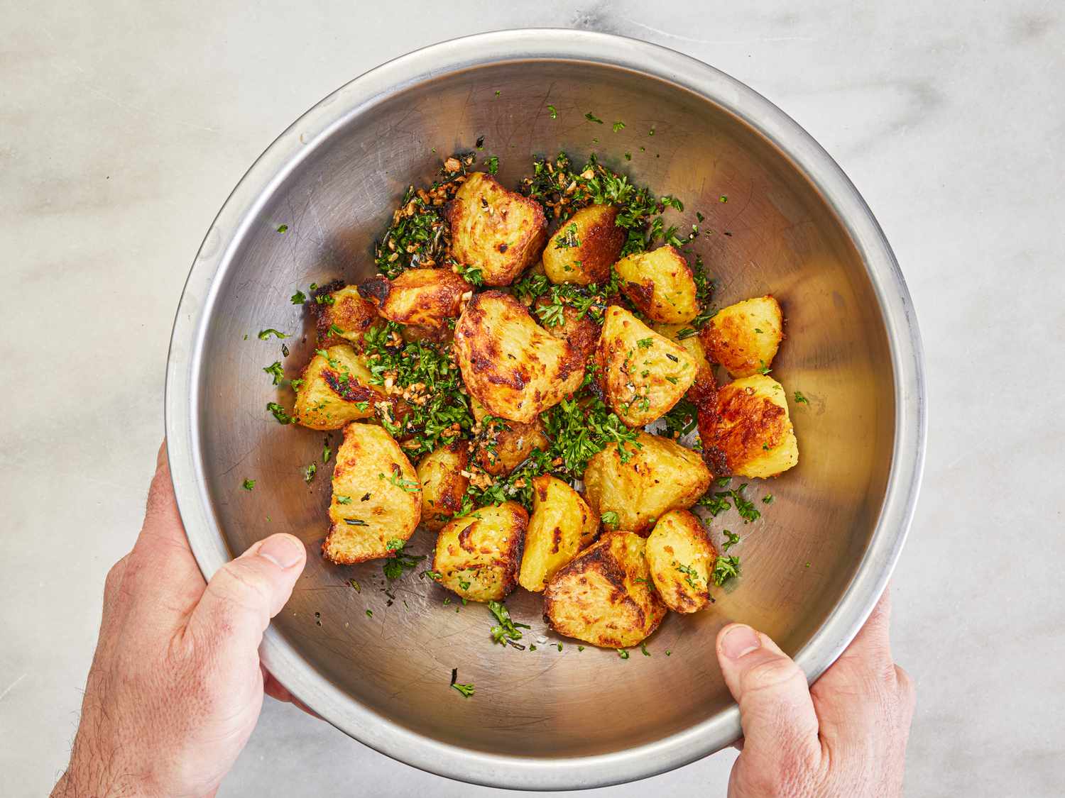 Overhead view of tossing potaotes with herbs