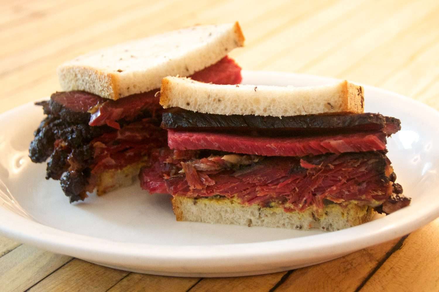 Pastrami sandwich on white serving plate.