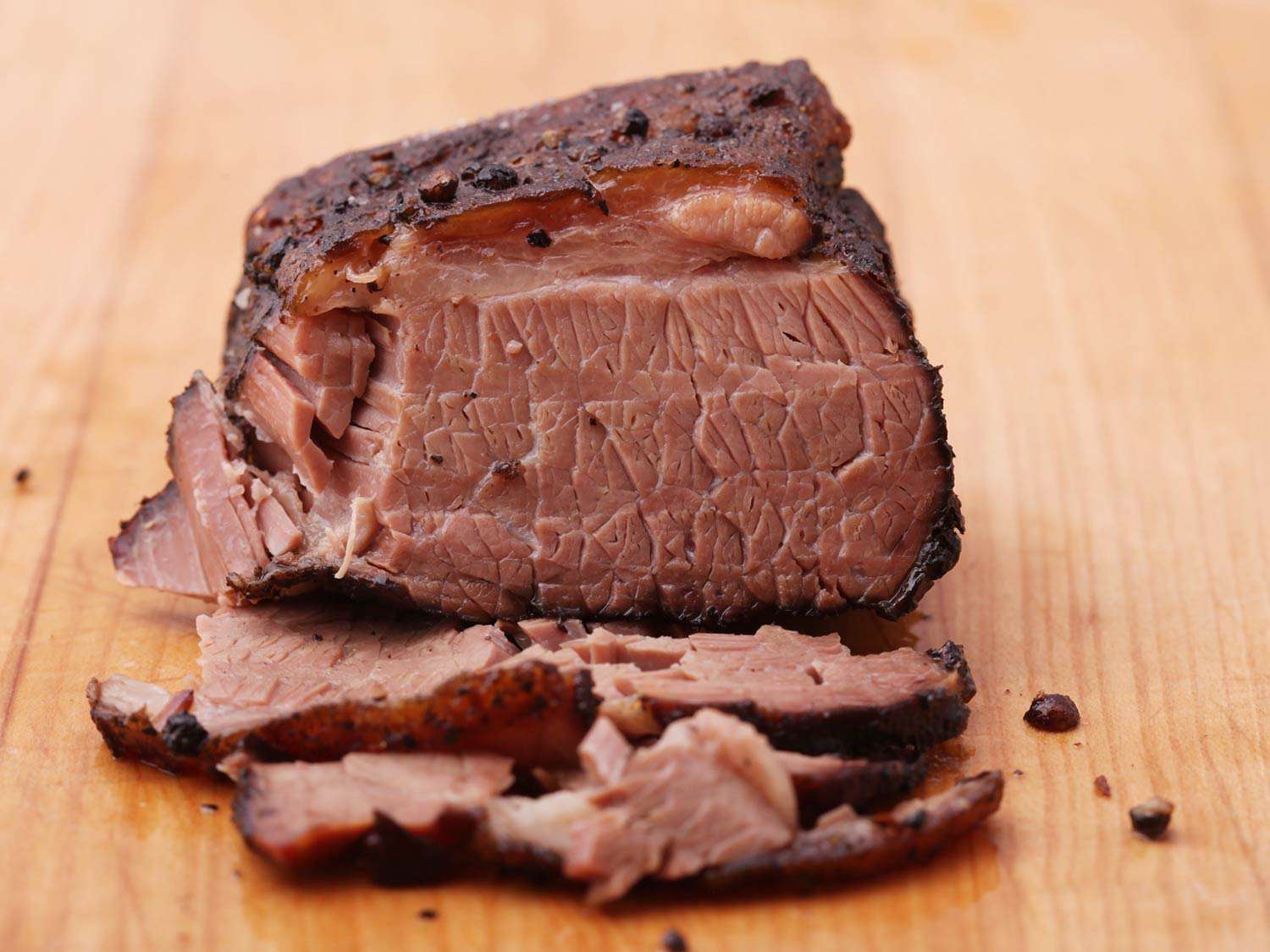 Piece of slow-cooked brisket on cutting board with several pieces sliced off.