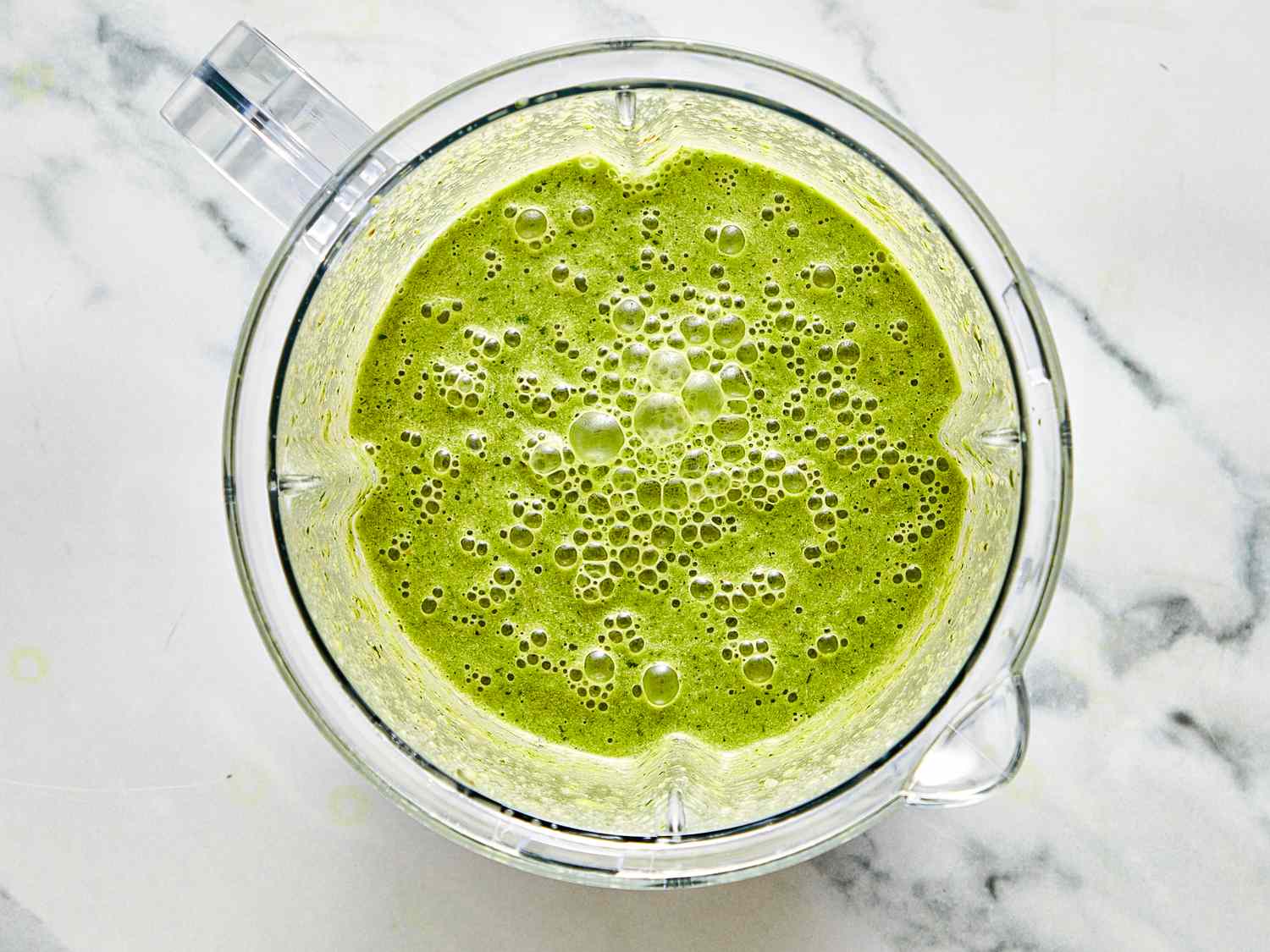 Green smoothie mixture in a blender jar on a countertop
