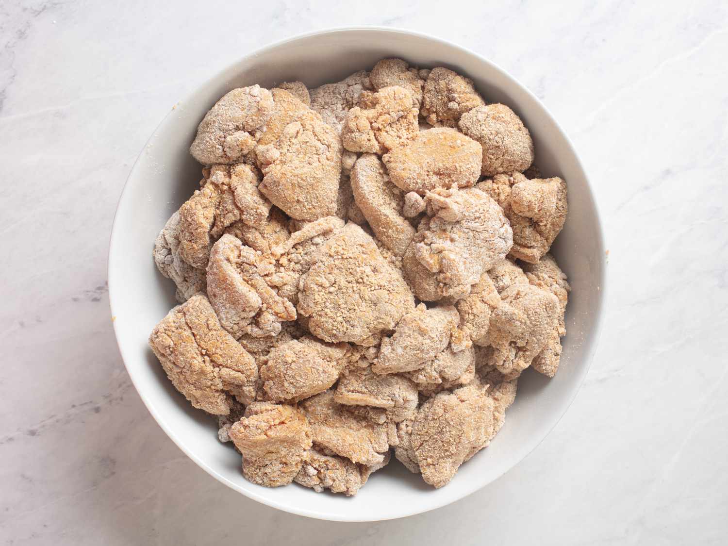 Dry-coated chicken pieces in a white bowl. 