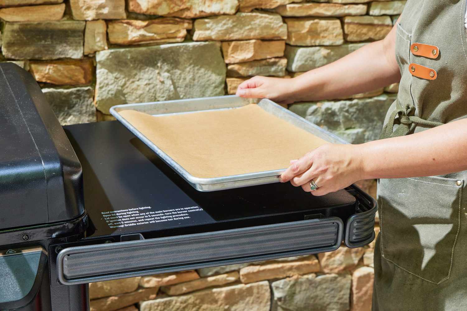 A person places a tray on the Traeger Flatrock Flat Top Grill