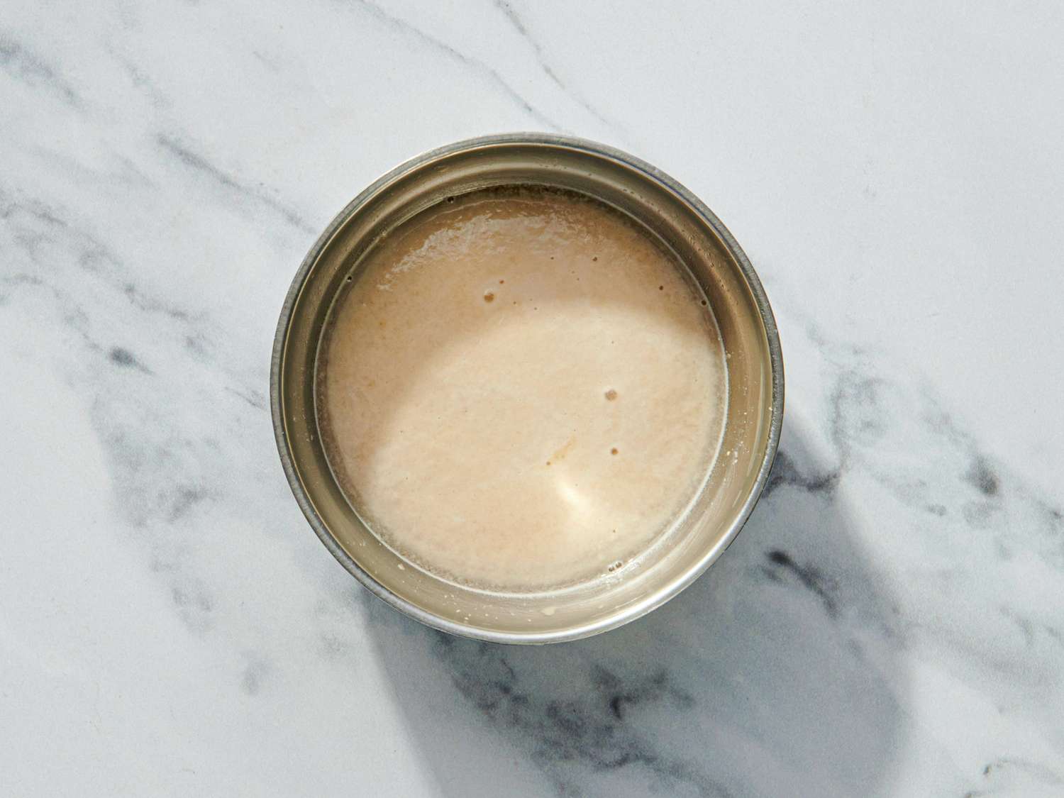 A bowl containing a pale smooth liquid mixture on a marble surface