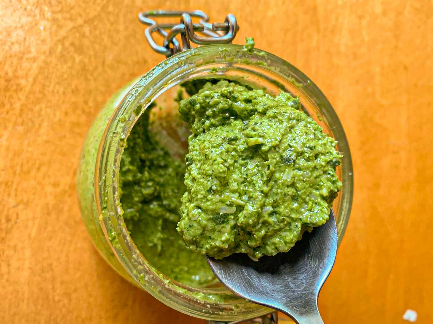 Jar of pesto with a spoon scooping some out