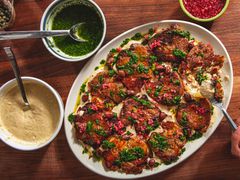 Platter of smashed double sauce potatoes with garnishes on a wooden table