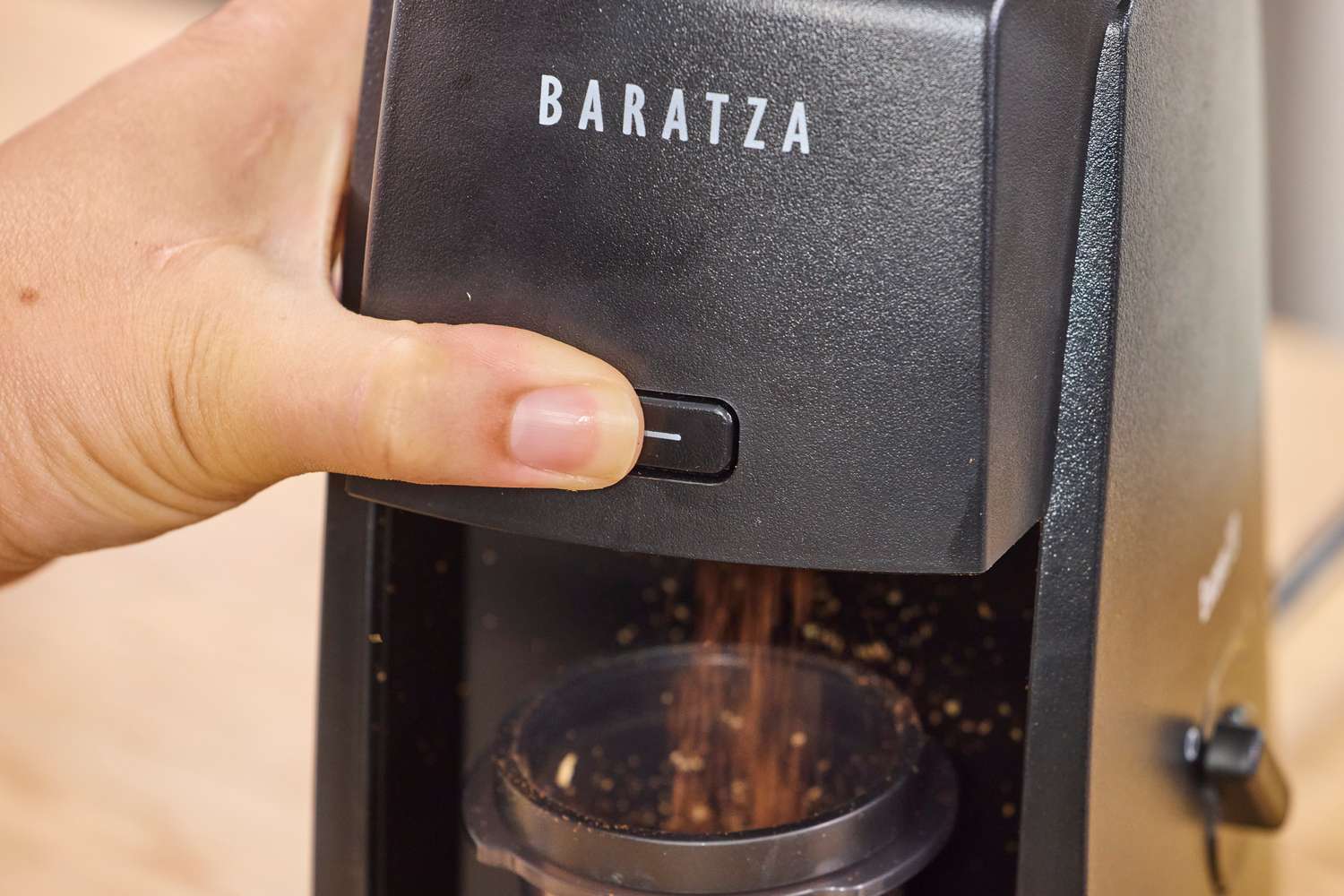 A person presses a button on the Baratza Encore ESP Coffee Grinder