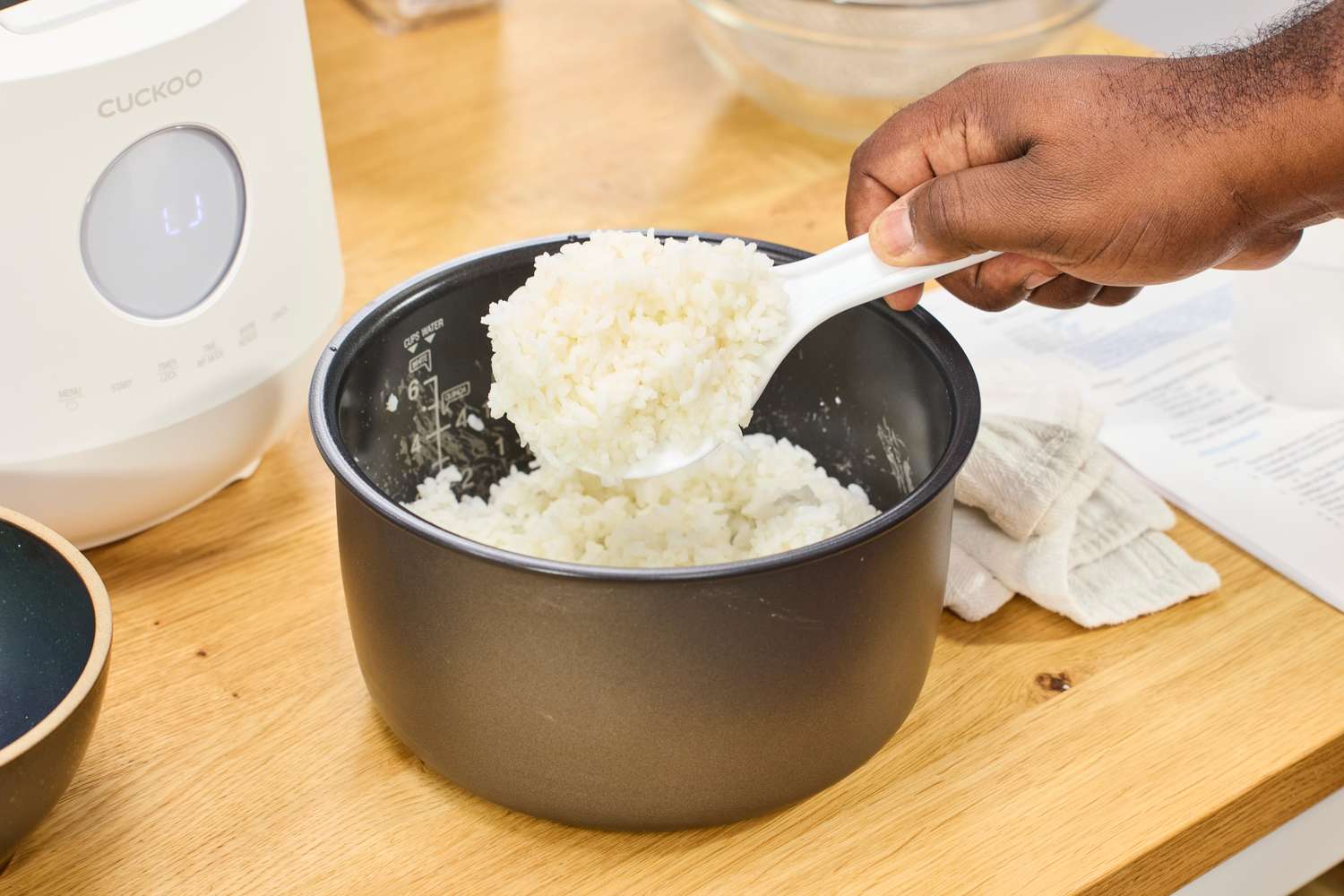 A person scoops rice from the Cuckoo 6-Cup Micom Rice Cooker