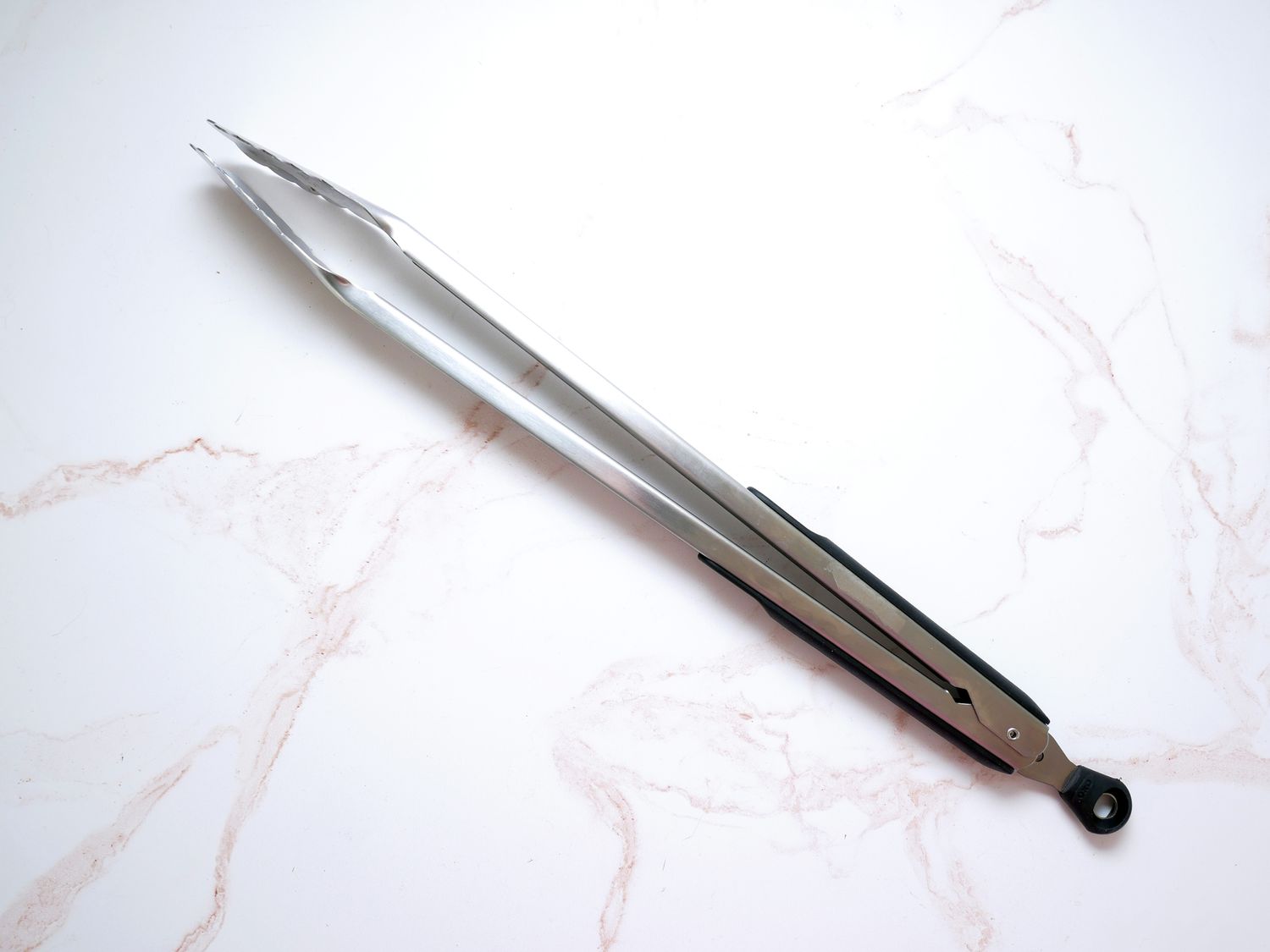 the oxo 16-inch kitchen tongs on a pink and white marble surface