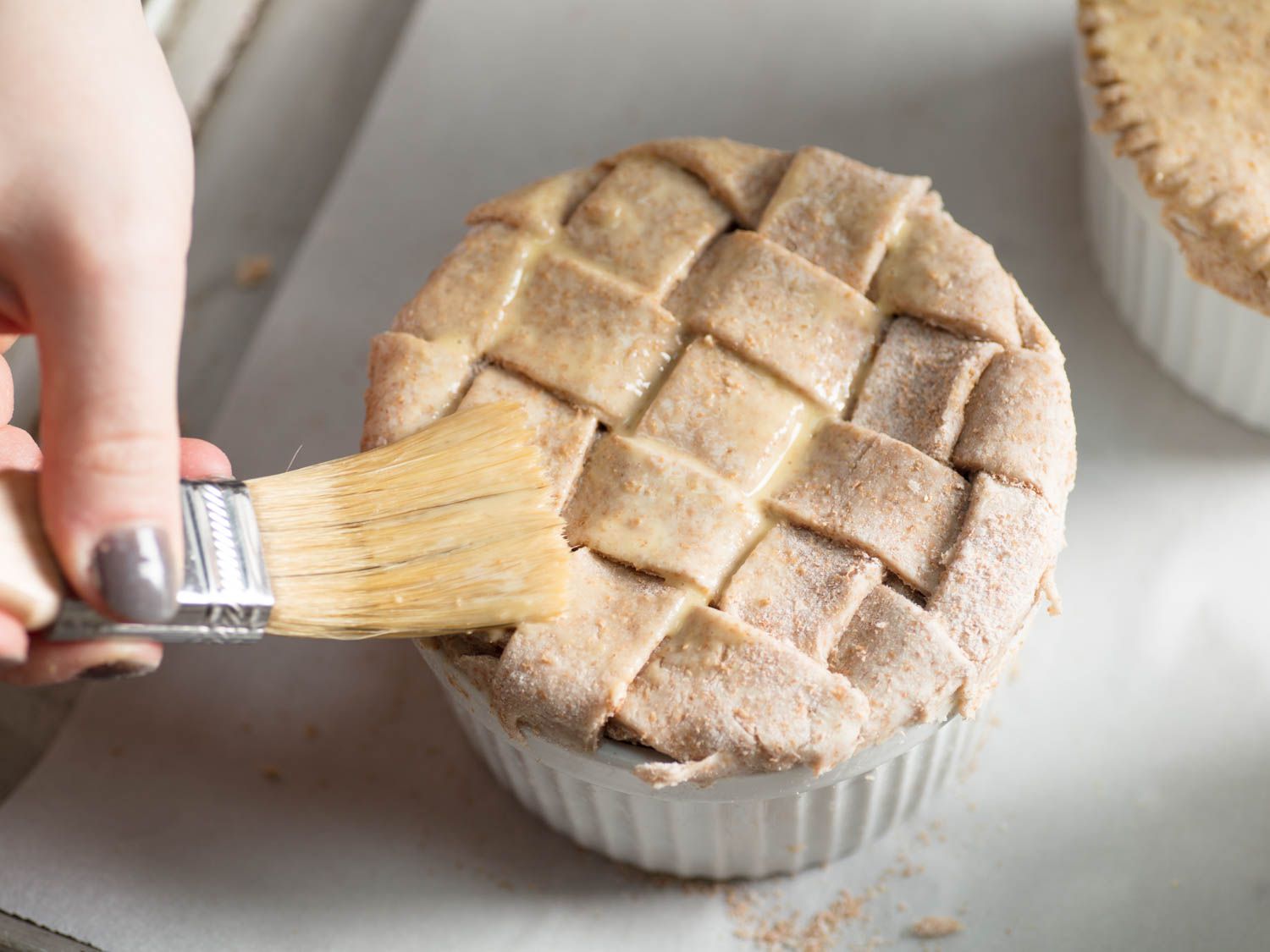 Brushing egg wash on a lattice-topped chicken pot pie.