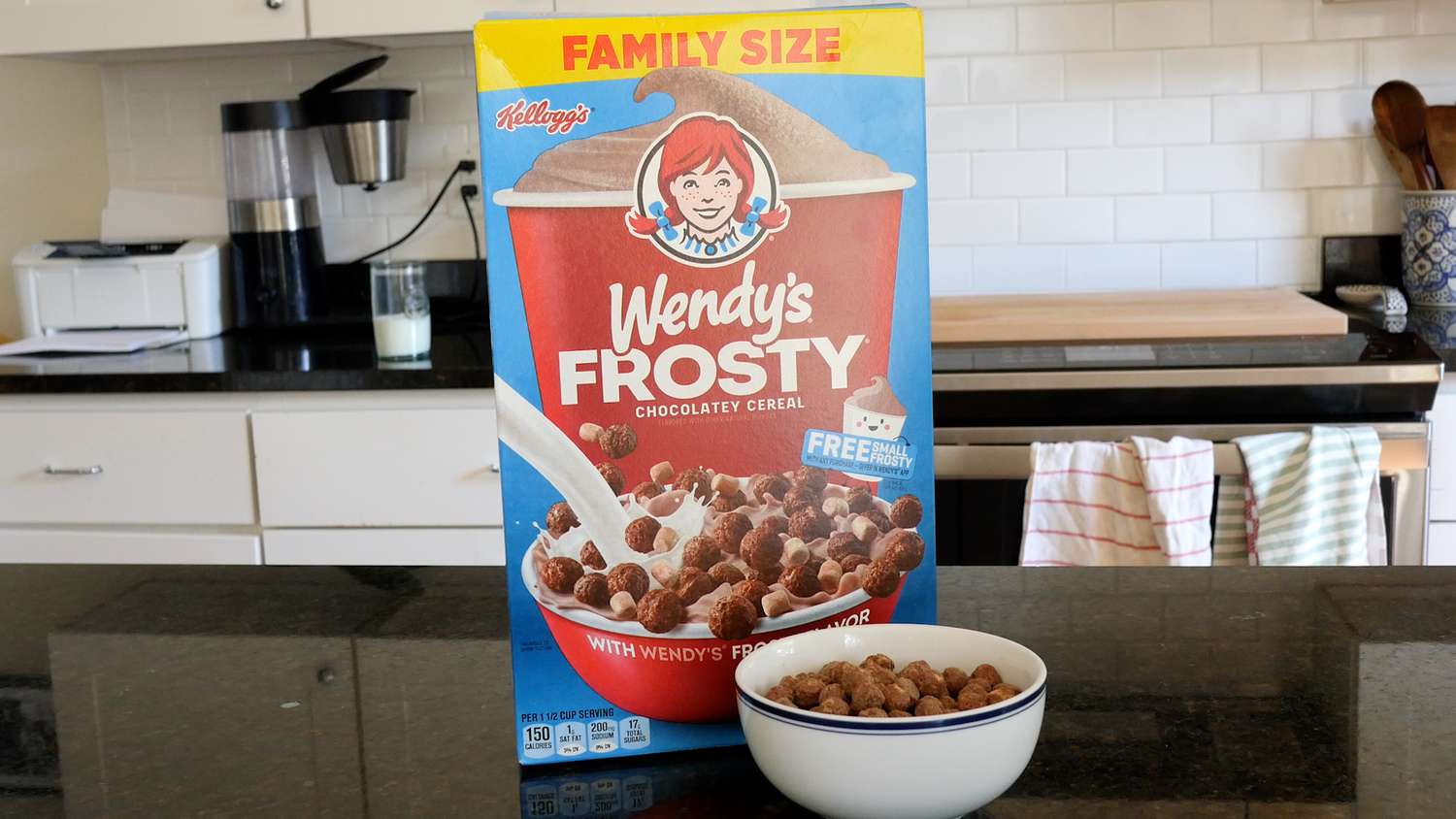 A box of Wendy's Frosty Cereal (and a bowl of the cereal) atop a black counter. 