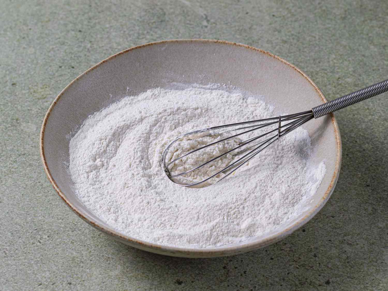 The dry pancake ingredients mixed together in a ceramic bowl with whisk
