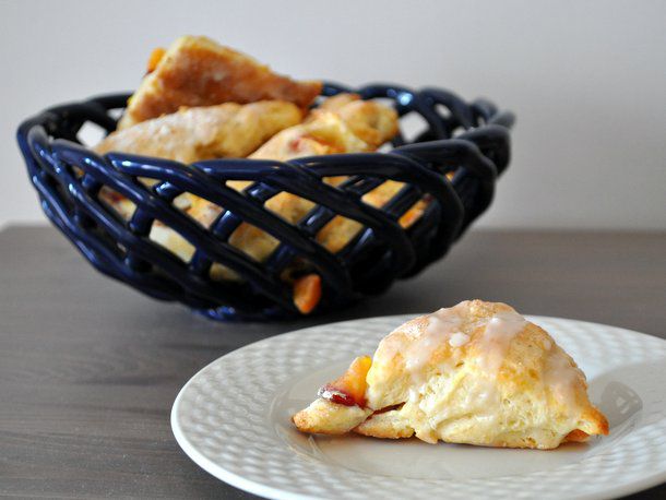 Mini peach scones served in a braided/woven ceramic bowl. One scone has been pulled from the bowl and transferred to a white plate.