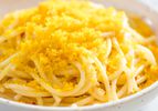 Bottarga grated over a bowl of spaghetti.