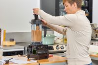 A person using a tool inside of the Vitamix 5200 Professional-Grade Blender to blend items better