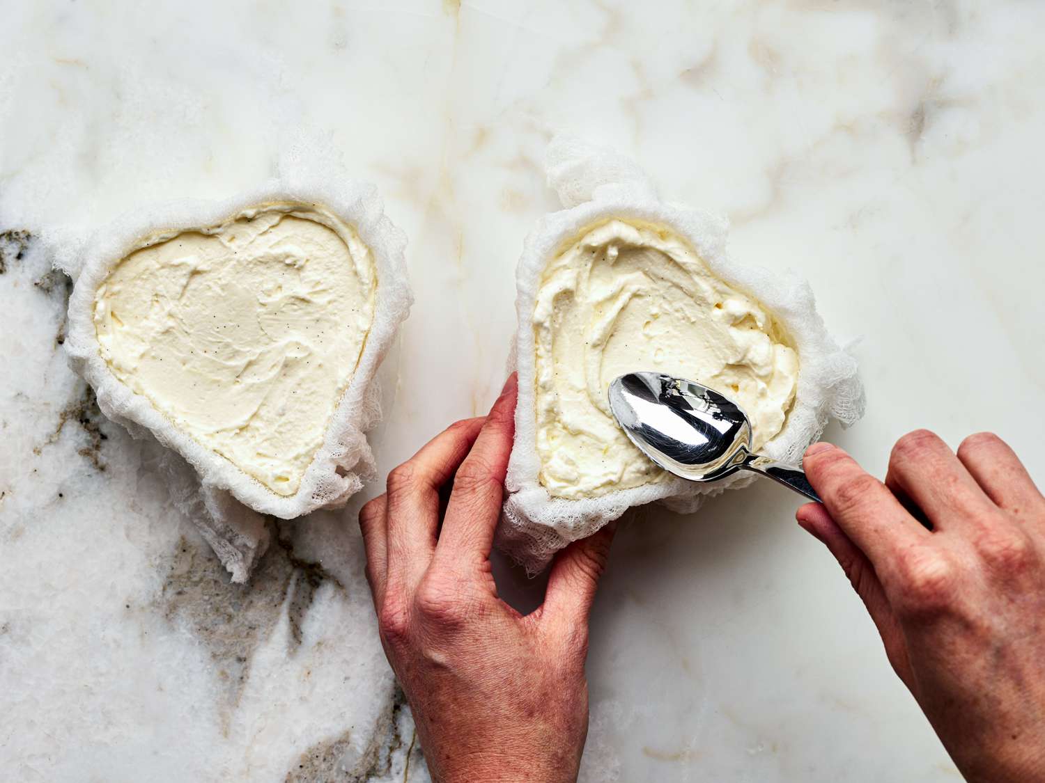 Overhead view of adding cream cheese mixture to cheesecloth lined molds