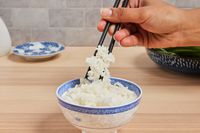 a person using chopsticks to pick up rice