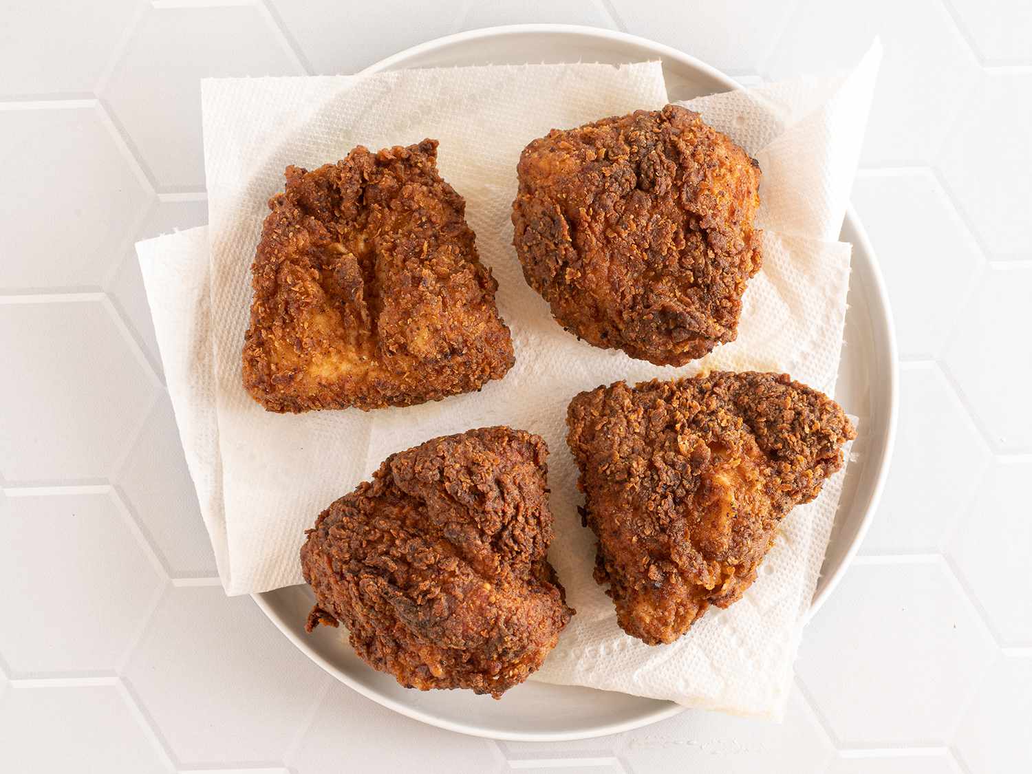 Fried chicken breasts resting on paper towels on a plate.
