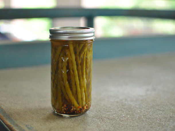 A pint jar of pickled garlic scapes sitting on a table.