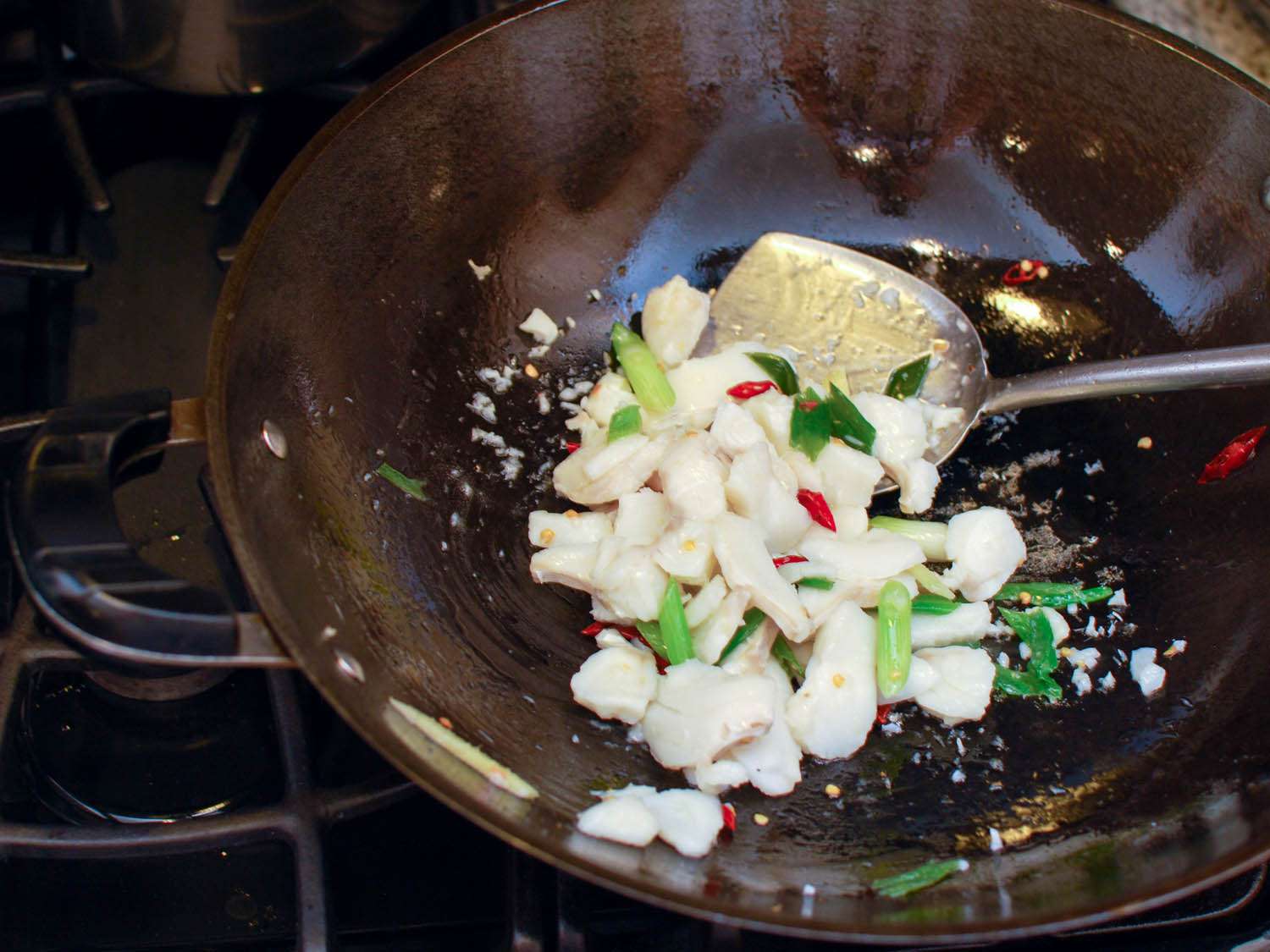 Velveted meat being tossed with vegetables and spices in a wok.