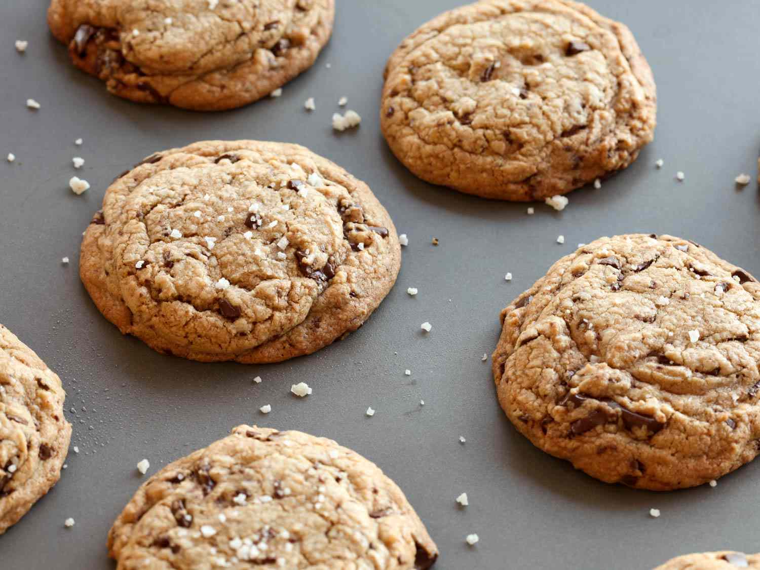 Chocolate chip cookies with craggy tops on a grey background.