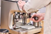 A person adjusts the portafilter on the Breville The Oracle Dual Boiler Espresso Machine