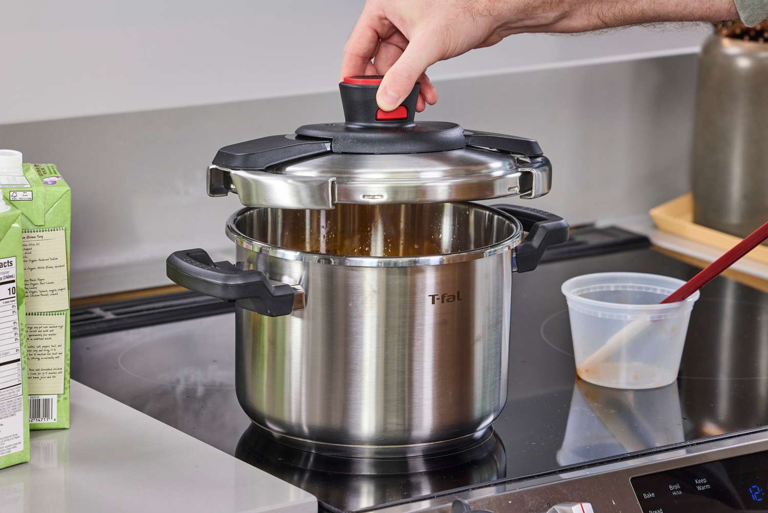 A hand placing the lid on the T-Fal Clipso Pressure Cooker