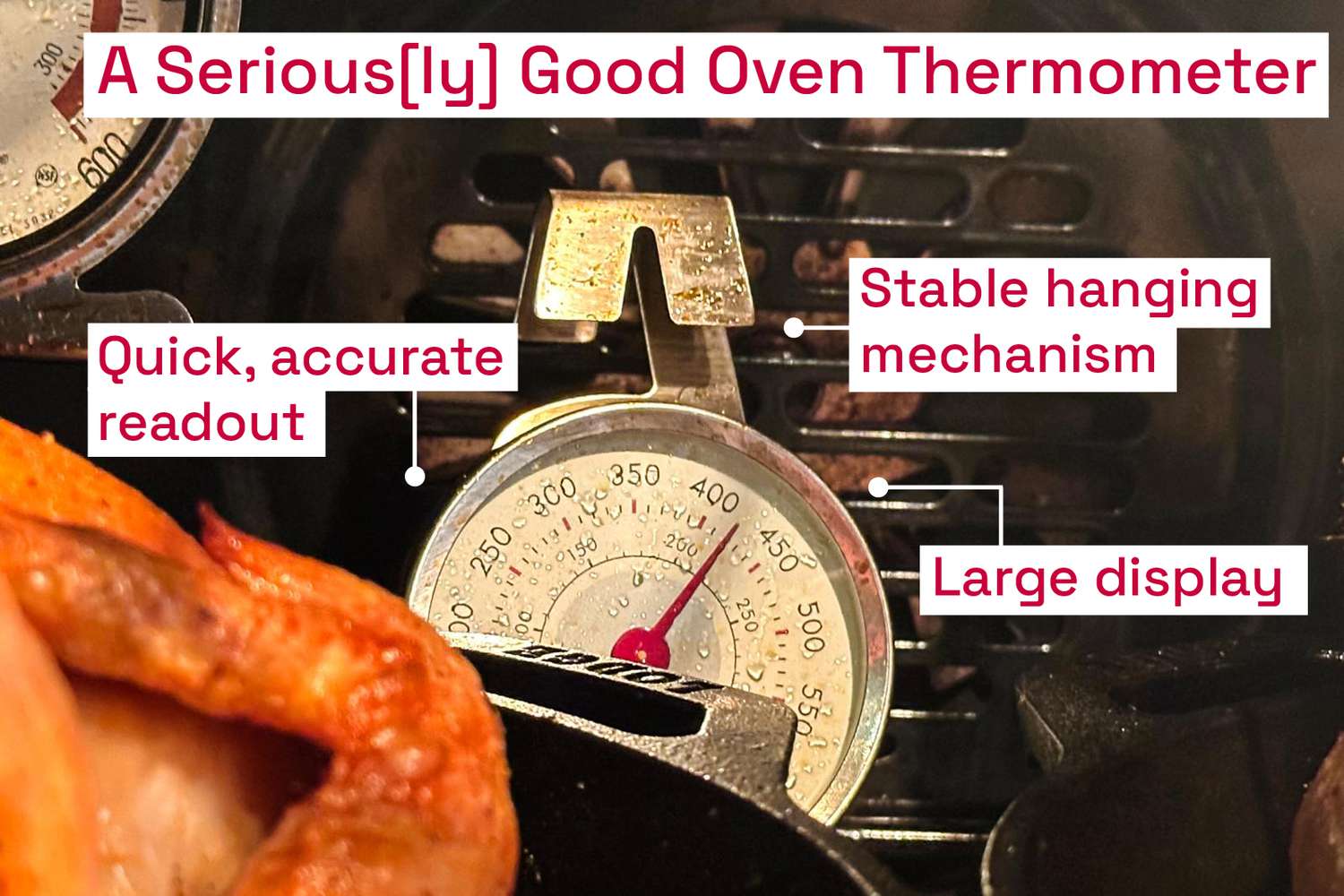 An analog oven thermometer hanging in an oven, behind a roasting chicken.