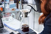 Person pouring water into a Kalita Wave 185 Dripper in a lab setting