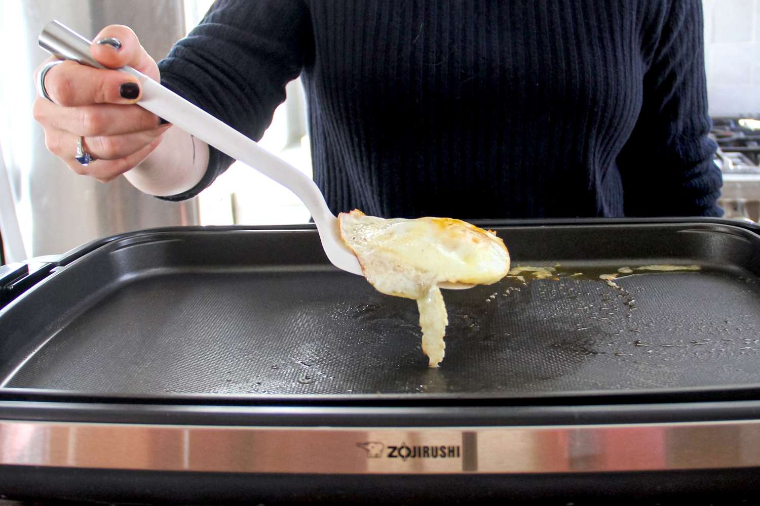 A person using the Material Soft-Edged Turner to flip food