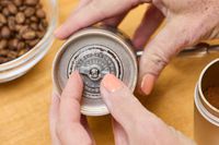 A person removes a piece from the 1Zpresso J Manual Coffee Grinder