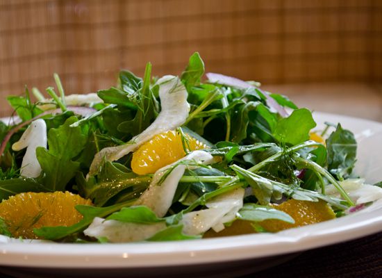 Arugula, fennel, and orange salad is served on a plate.