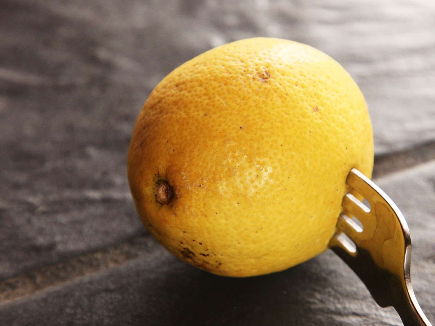 A fork piercing a whole lemon