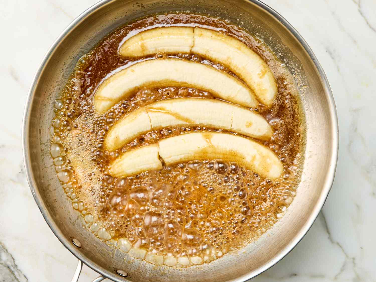 Banana slices caramelizing in a pan