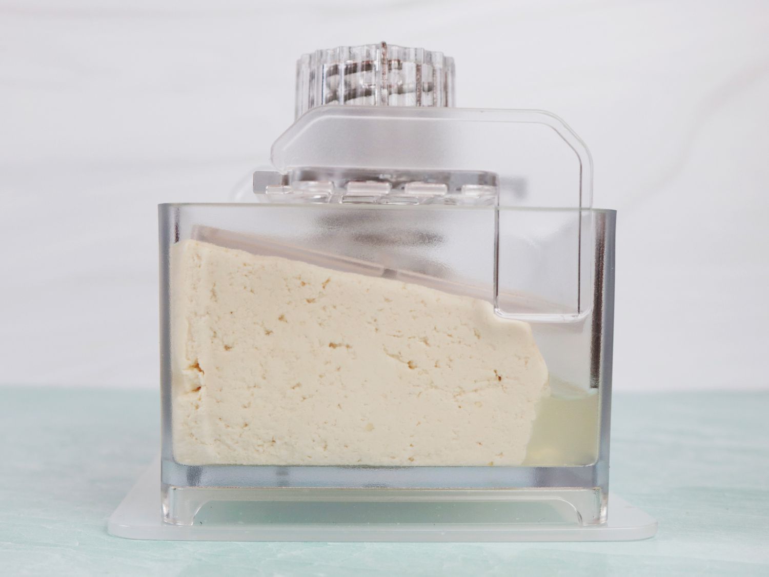 a tofu press that shows expressed water sitting on the tofu block