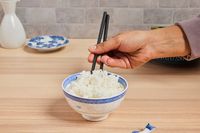 a person using chopsticks to eat rice