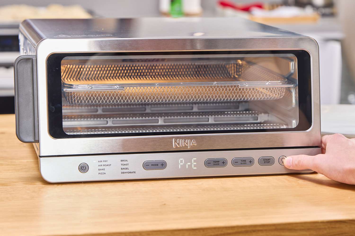 A person presses a button on the Ninja Flip Toaster Oven & Air Fryer