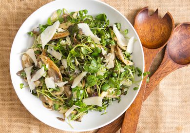 Overhead view of roasted oyster mushroom and watercress salad, served in a white bowl.