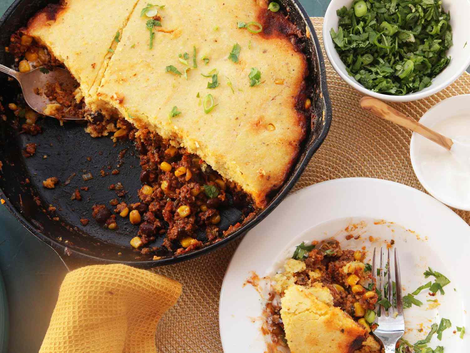 Skillet tamale pie with cornmeal crust and chopped scallions on the side, dished up 