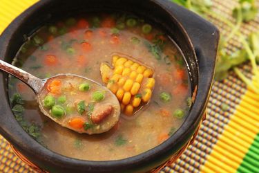 A bowl of ajiaco negro. A spoon raises a bite from the bowl.