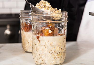 Preparing overnight oats in mason jars with oats milk and spiced apple topping