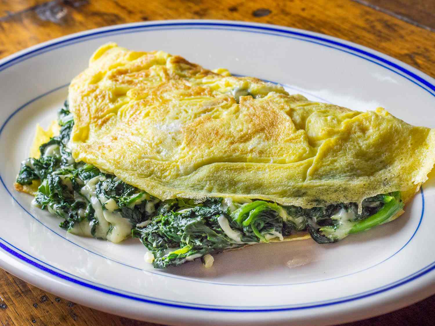 Florentine spinach and cheese omelette on a white plate with a blue rim.