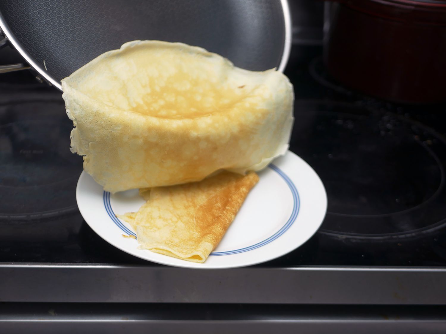 sliding a crepe out of the hexclad plan onto a plate