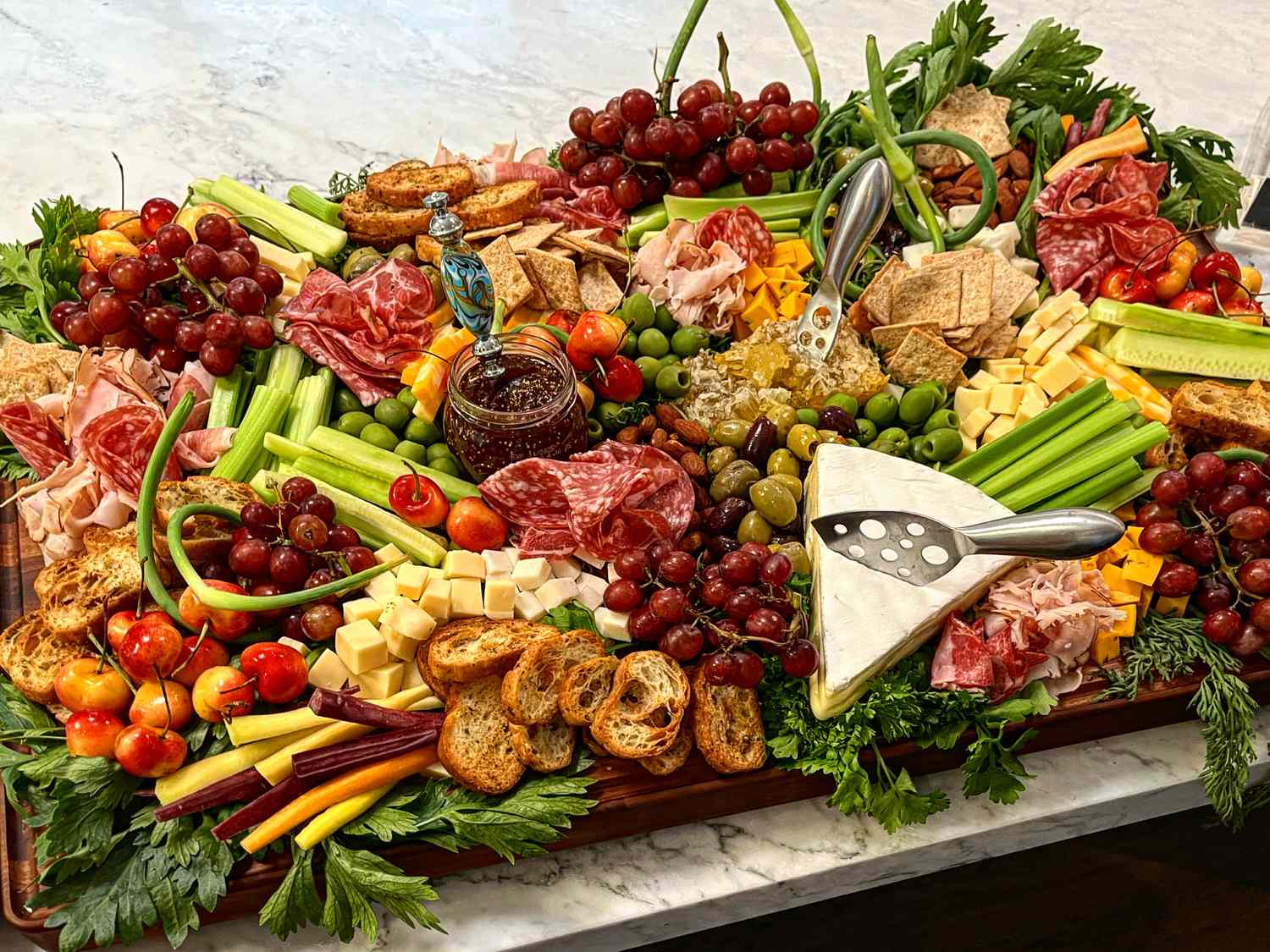 An arrangement of a grazing board adorned with various cheeses meats fruits bread slices and garnishes displayed on a table